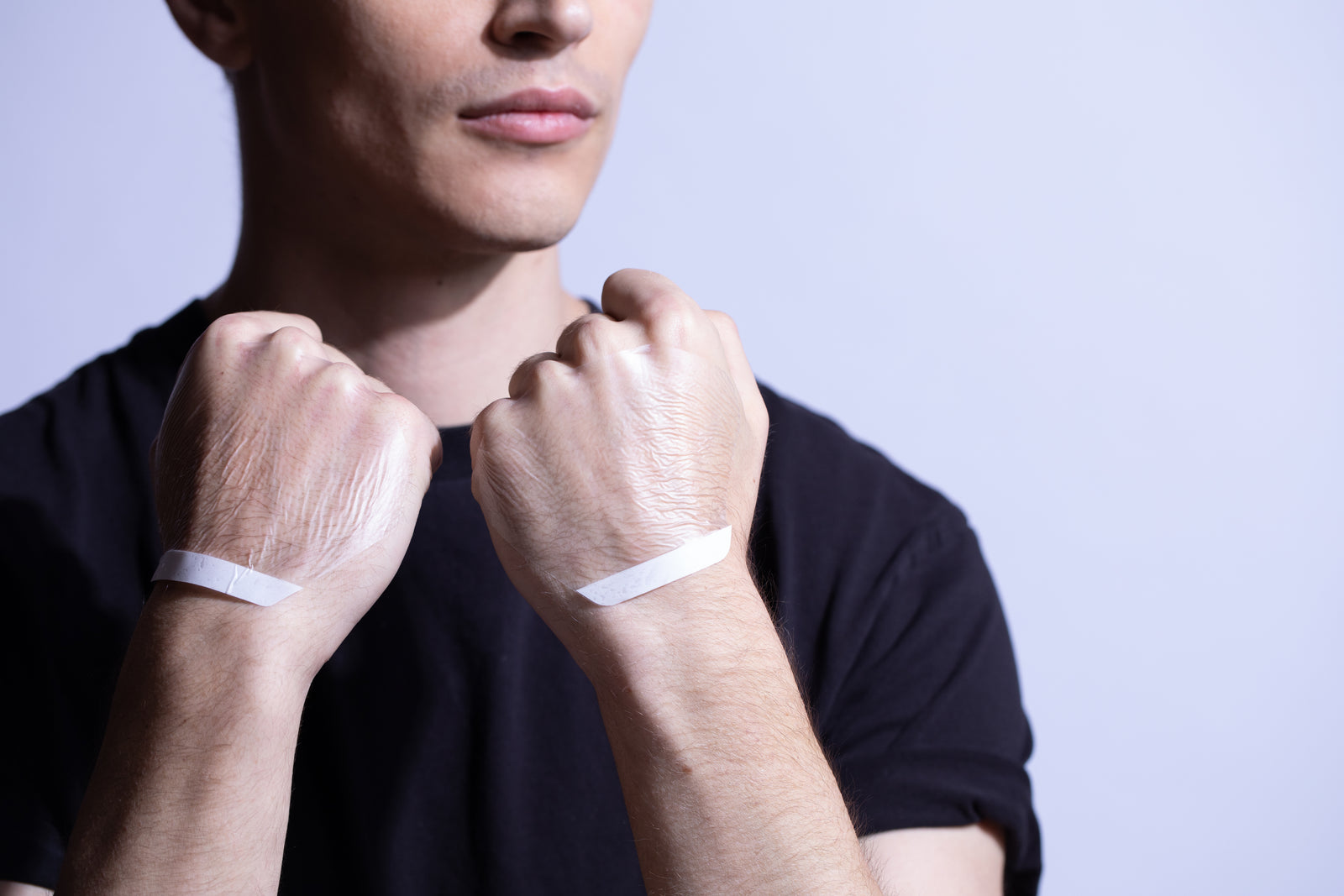 A person applying a transparent textured makeup product to the back of their hand, resembling a second skin makeup hand palette.